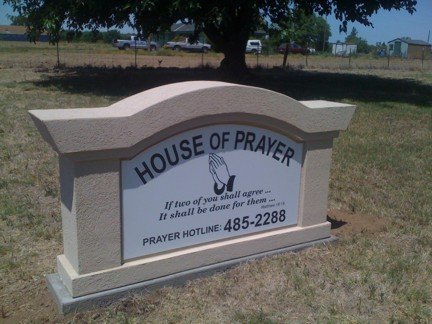 Sign for House of Prayer with contact details.