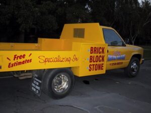 Yellow truck advertising brick, block, and stone services.