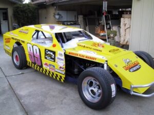 Yellow race car with number 99 parked outside