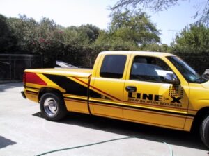 Yellow truck with Line-X spray-on bedliner branding.