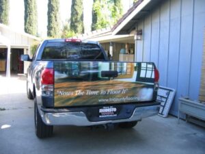 Truck with flooring advertisement parked in driveway.